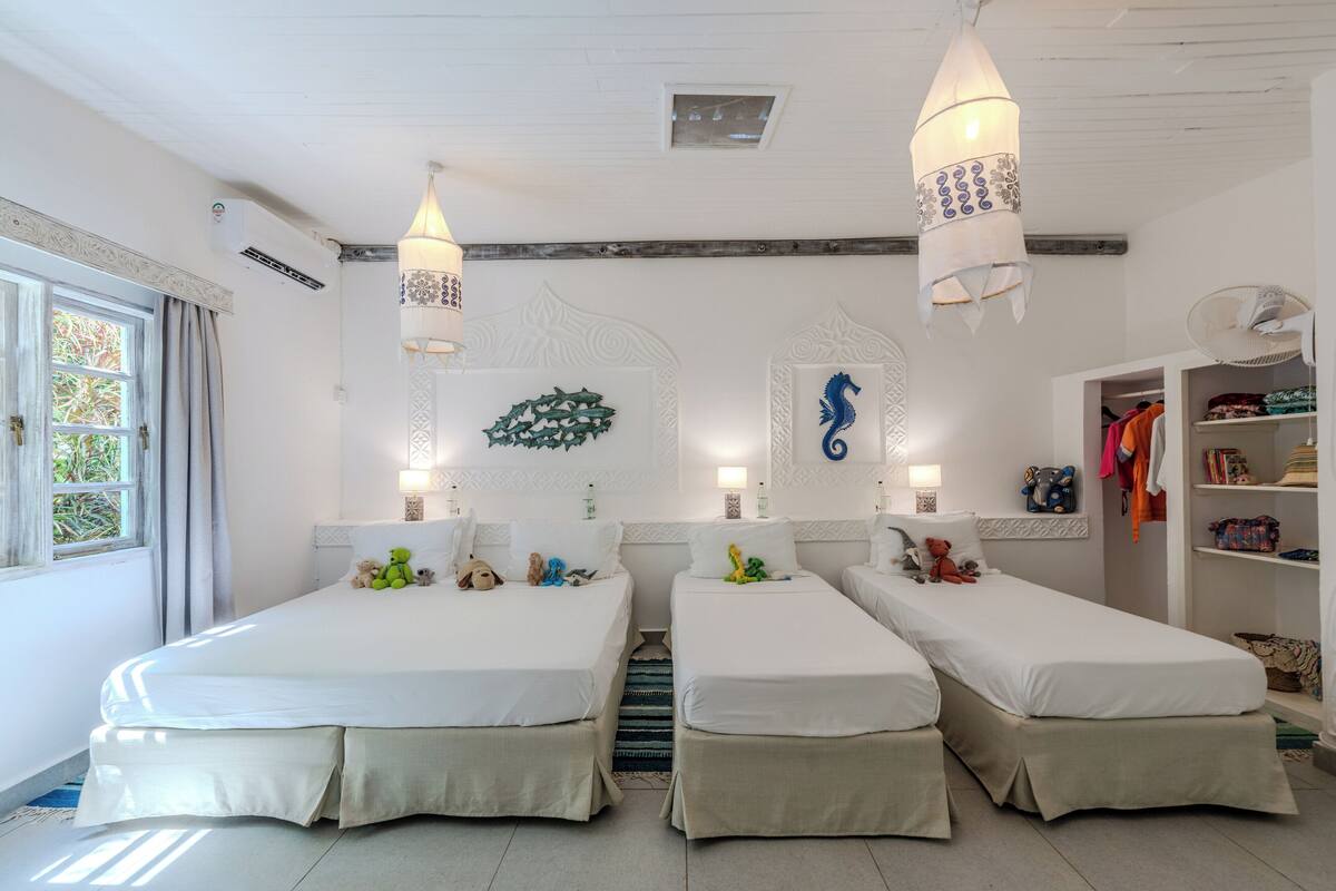 A hotel room with two single beds, a wardrobe, and a small seating area.
