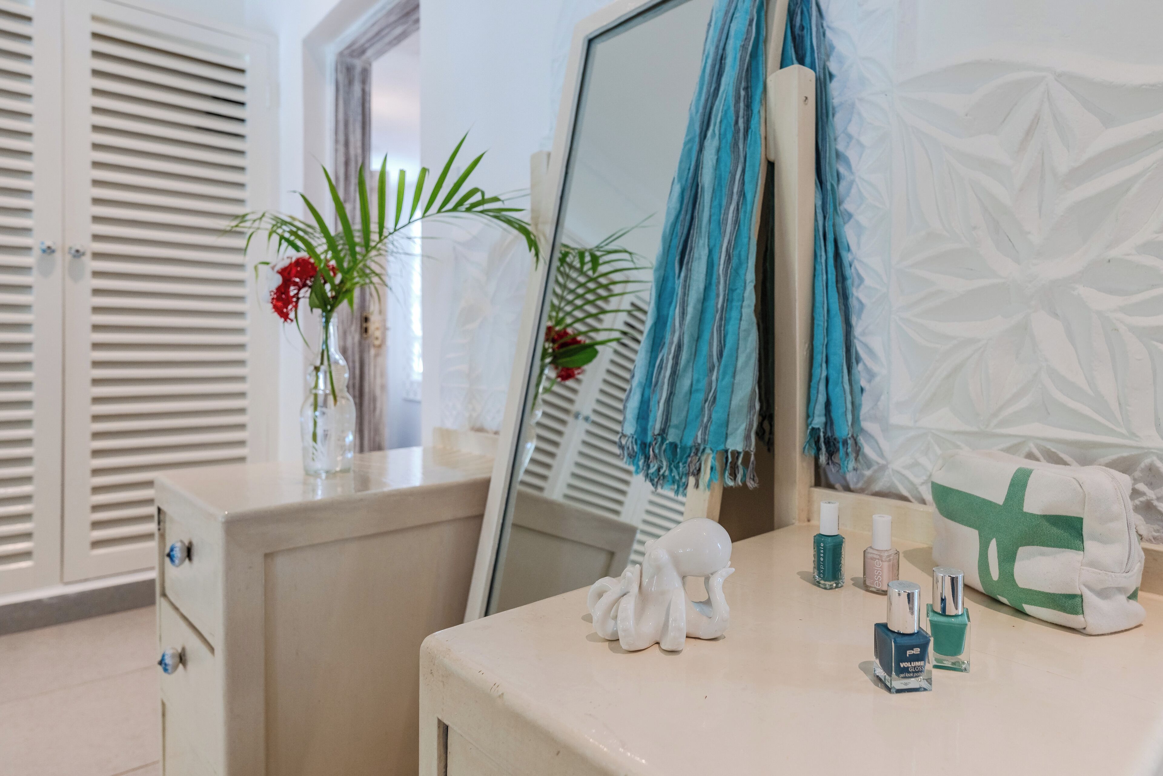 Une salle de bain équipée d’un meuble-lavabo, d’un miroir, d’un porte-serviettes et d’une plante décorative.