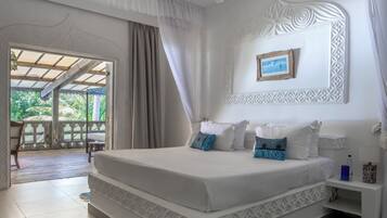 A bedroom with a large bed, a ceiling fan, a picture on the wall, and a view through the window.