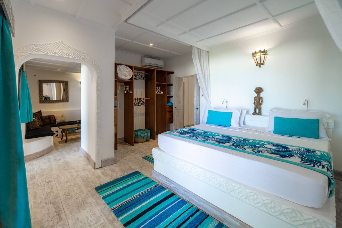 A spacious bedroom with a large bed, a walk-in closet, and a bathroom with a shower and a toilet.