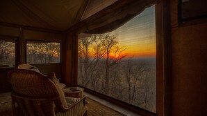 A room with a large window overlooking a landscape during sunset. - Ghoha Hills Savuti (Chobe National Park)