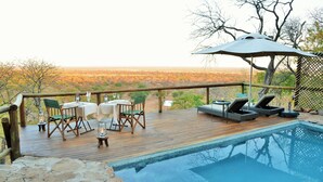 A wooden deck with a pool, outdoor seating, and a view of a savanna landscape. - Ghoha Hills Savuti (Chobe National Park)