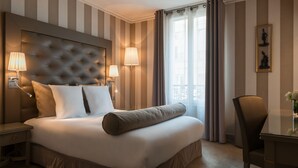 Habitación de hotel con una cama grande, dos lámparas de noche, cabecero, ventana con cortinas y un cuadro enmarcado en la pared.