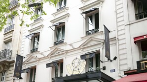 Un edificio con un emblema destacado, varios balcones y banderas que señalan que es un hotel.