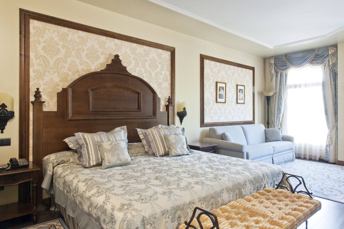 A bedroom with a large bed, a sofa, and a chair.