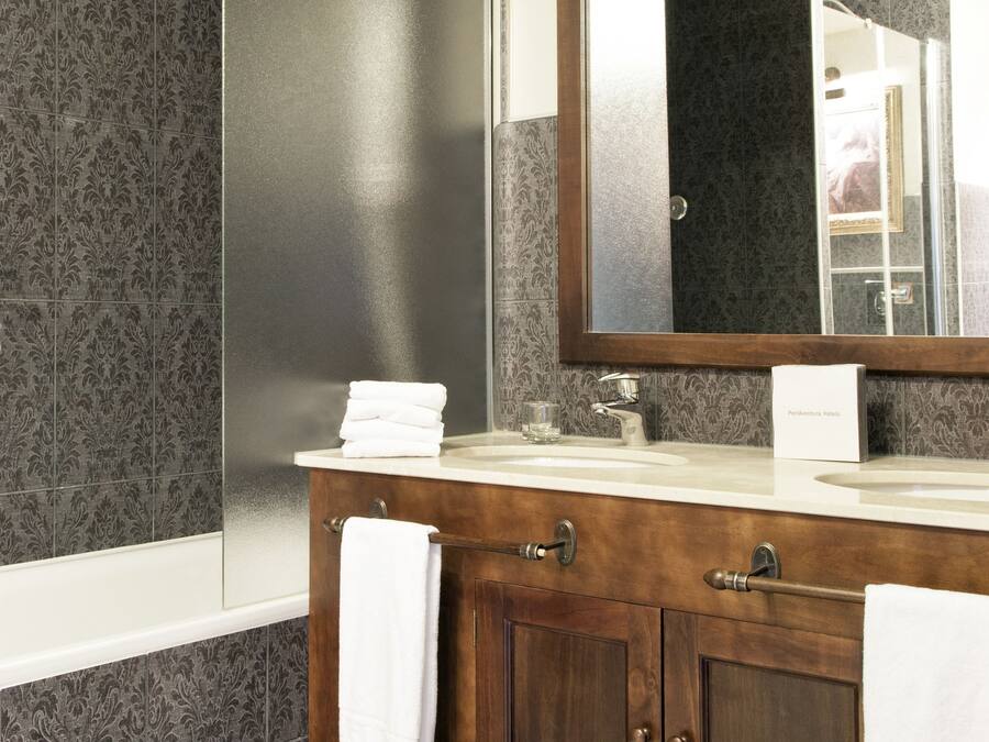 Un baño con lavabo doble, un espejo grande y una ducha.