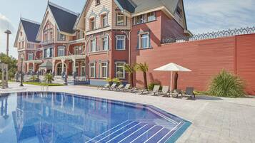 Una piscina al aire libre de temporada, sombrillas, tumbonas