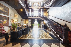 Un amplio vestíbulo con candelabro, escalera y mostrador de recepción.