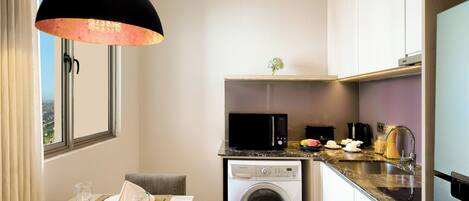 A compact kitchen with a washing machine, microwave, and a dining area with a table set for two.