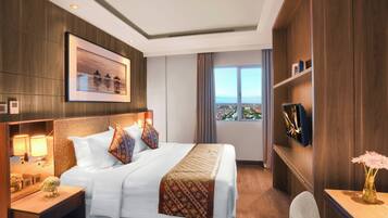 Une chambre d’hôtel avec un grand lit, des lampes de chevet, un téléviseur fixé au mur et une fenêtre donnant sur un beau paysage.