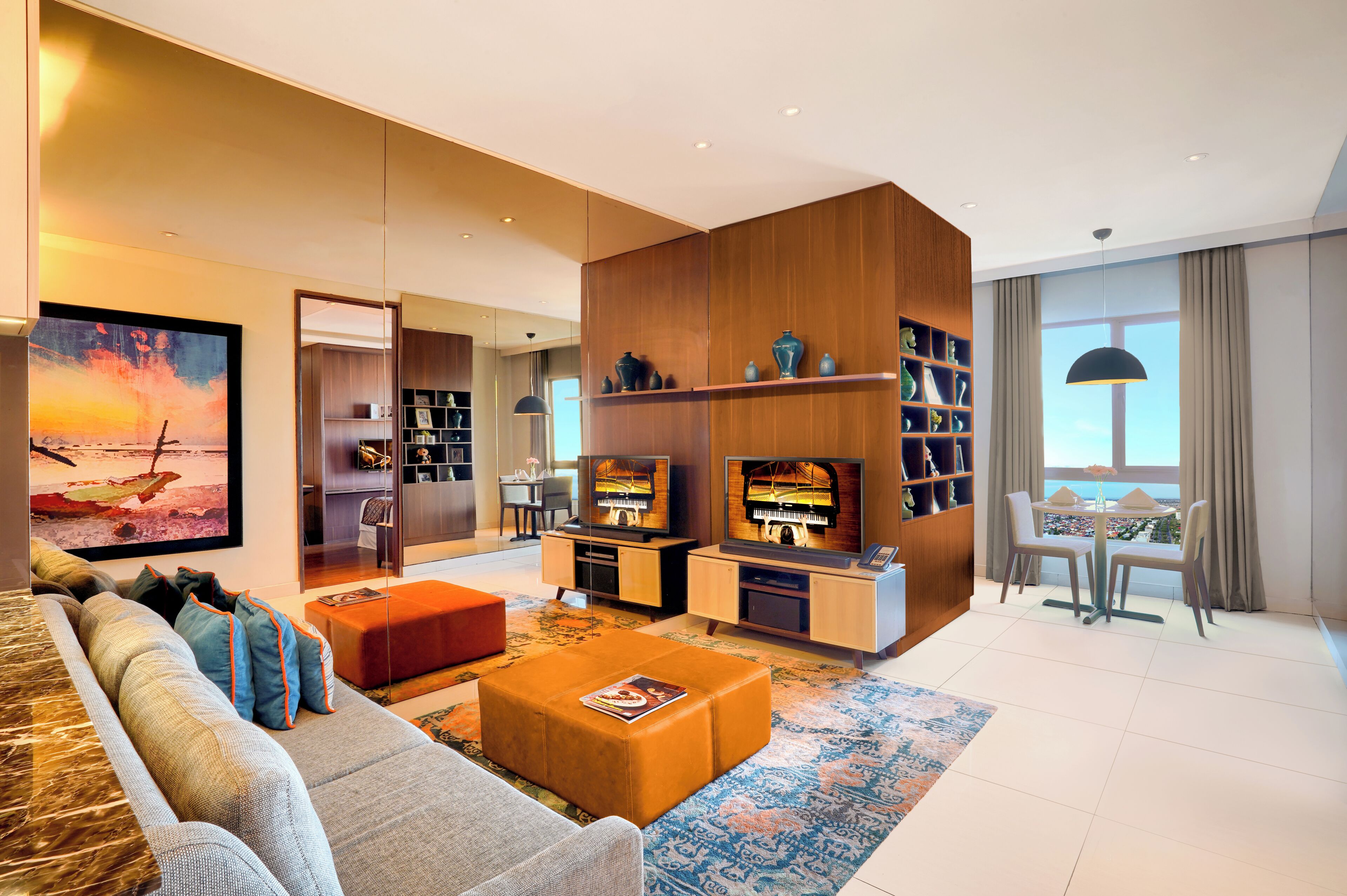 A modern living room with a sofa, ottoman, TV, and bookshelf.