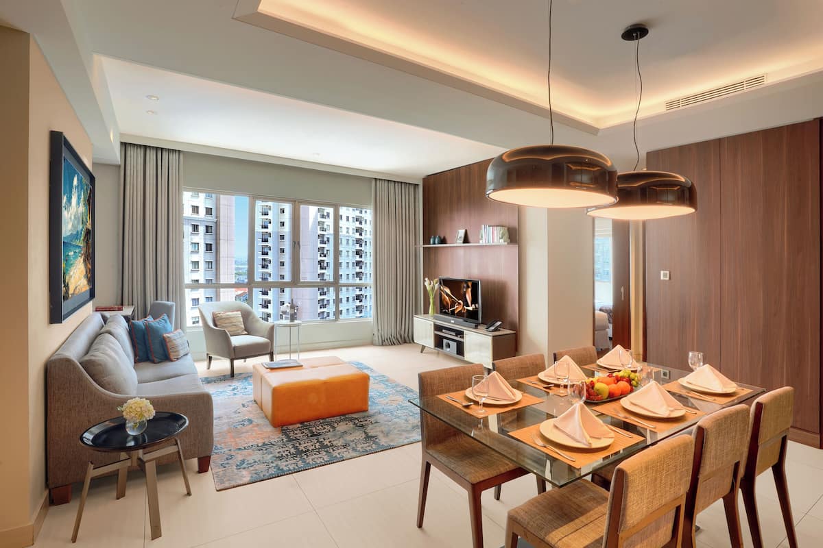 A modern living room with a sofa, coffee table, and dining area with a glass table and chairs.