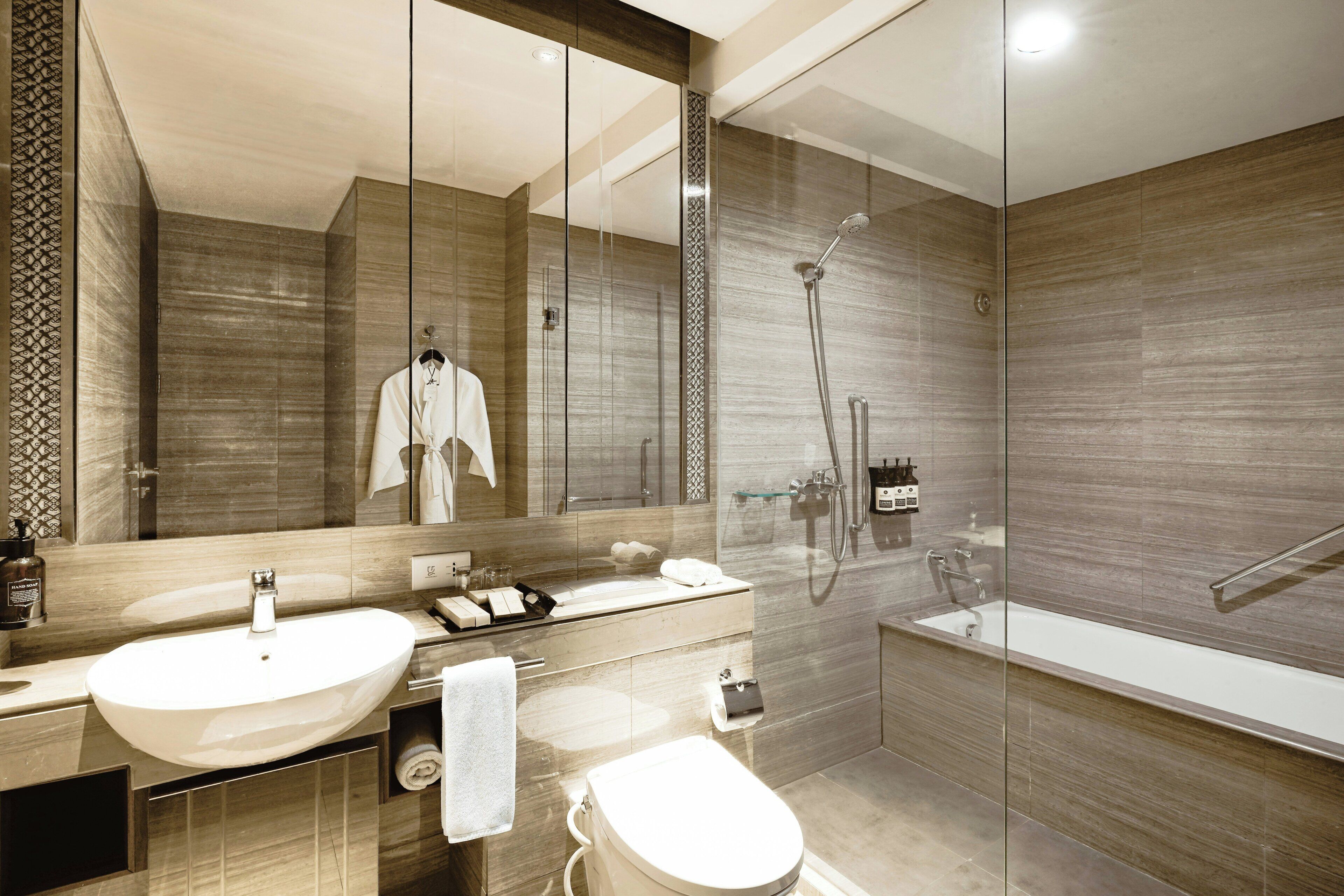 Un baño moderno con un espejo grande, un lavabo, un inodoro y una ducha.