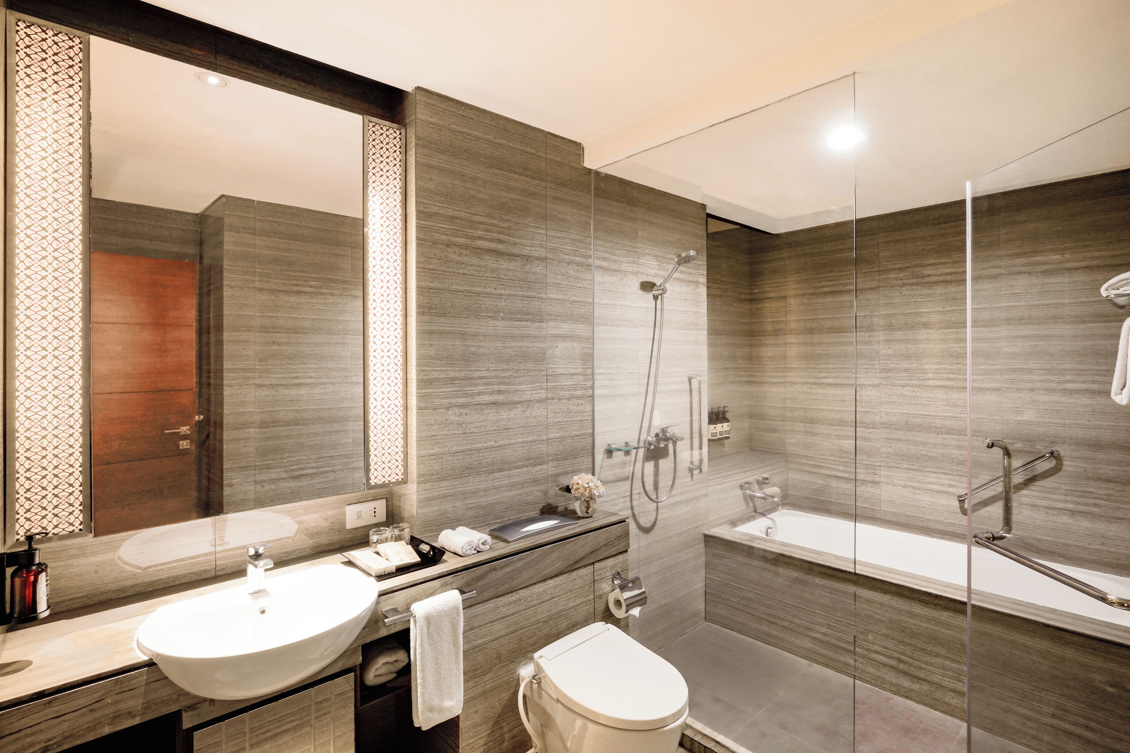 Un baño moderno con un espejo grande, un lavabo, un inodoro y una zona de ducha.