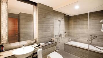 Un baño moderno con un espejo grande, un lavabo, un inodoro y una zona de ducha.