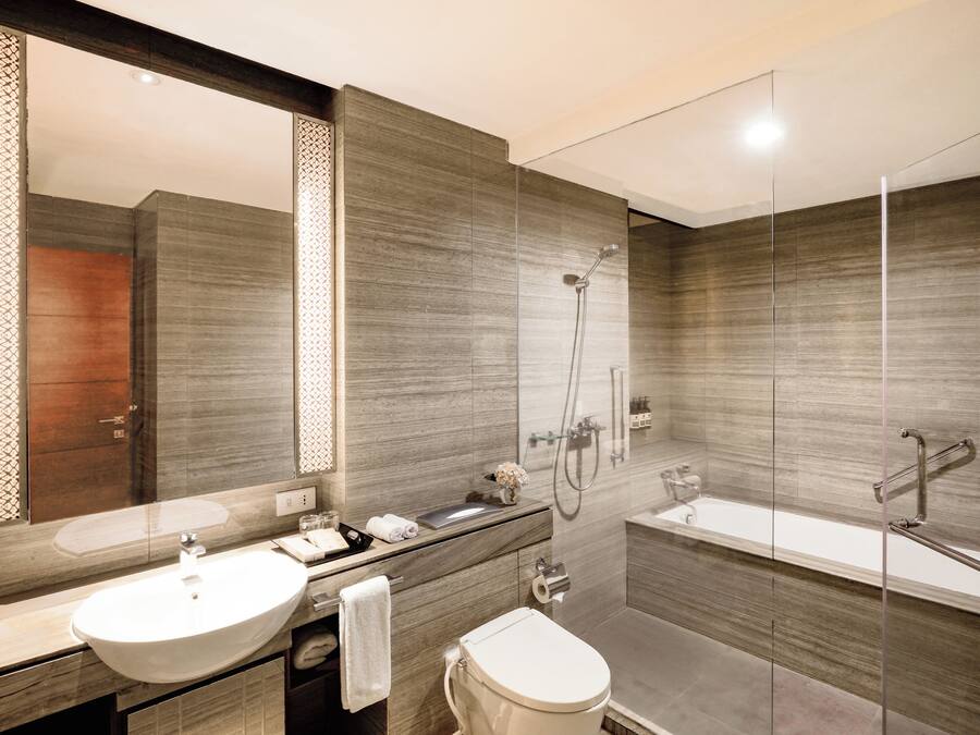 Un baño moderno con un espejo grande, un lavabo, un inodoro y una zona de ducha.