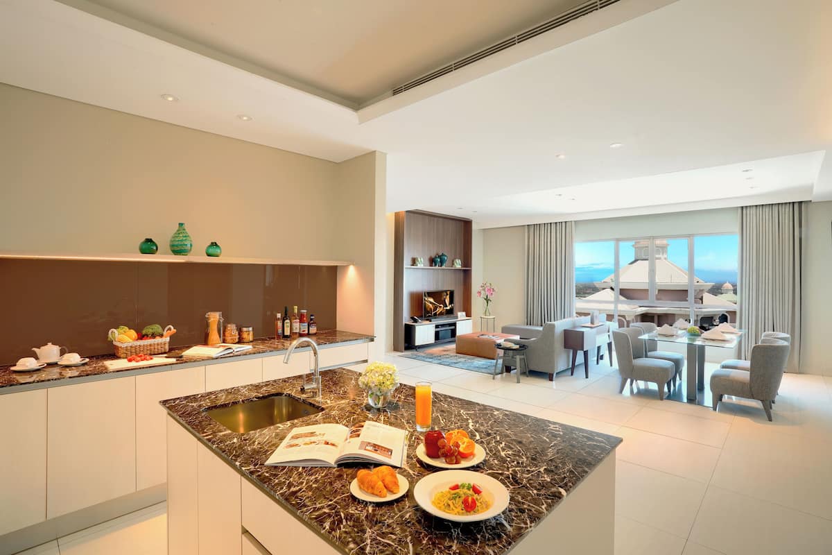 A modern kitchen with a marble island, dining area with a view, and a living room with a fireplace.