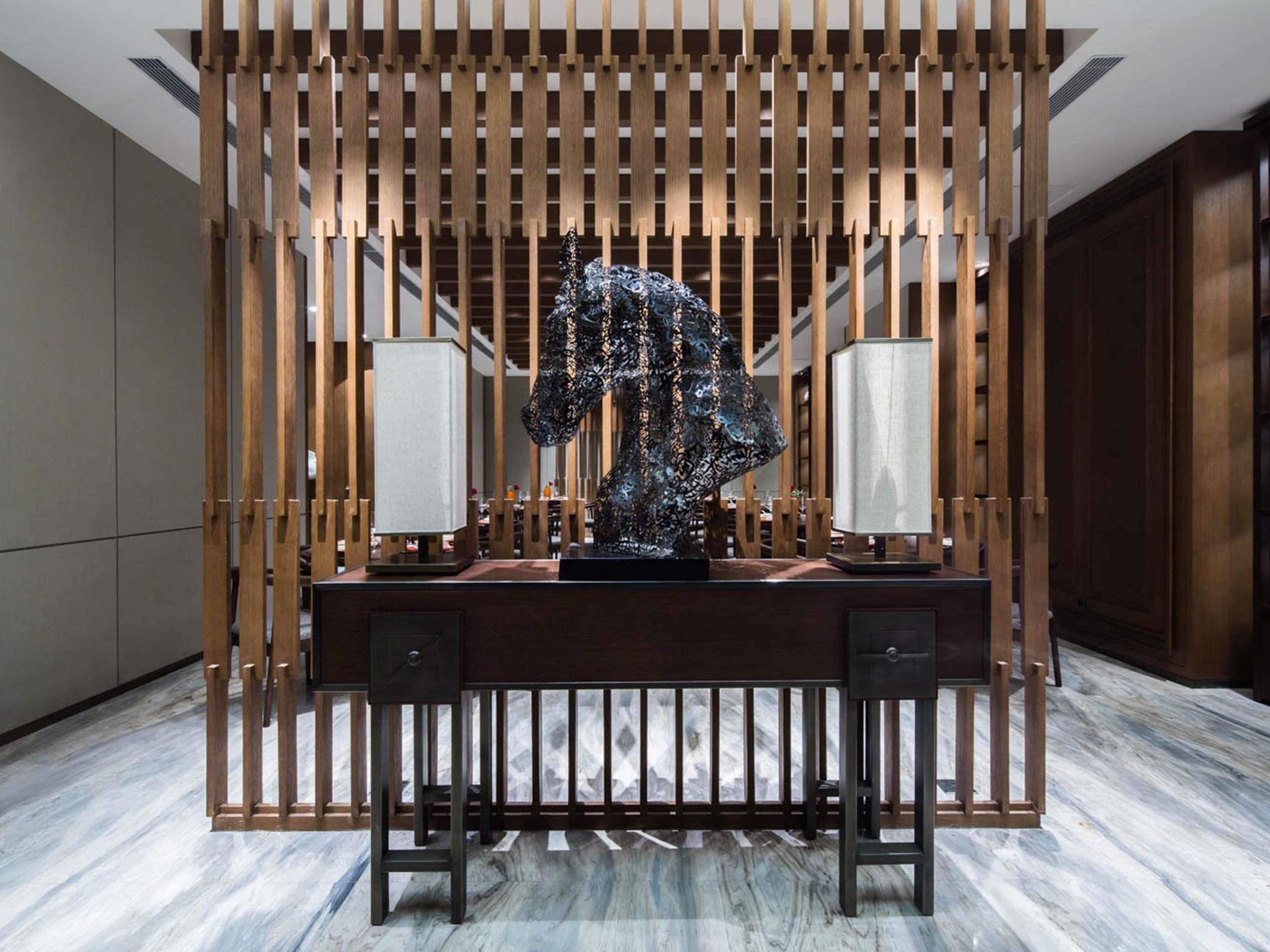 A modern interior with a desk, two lamps, and a decorative sculpture.