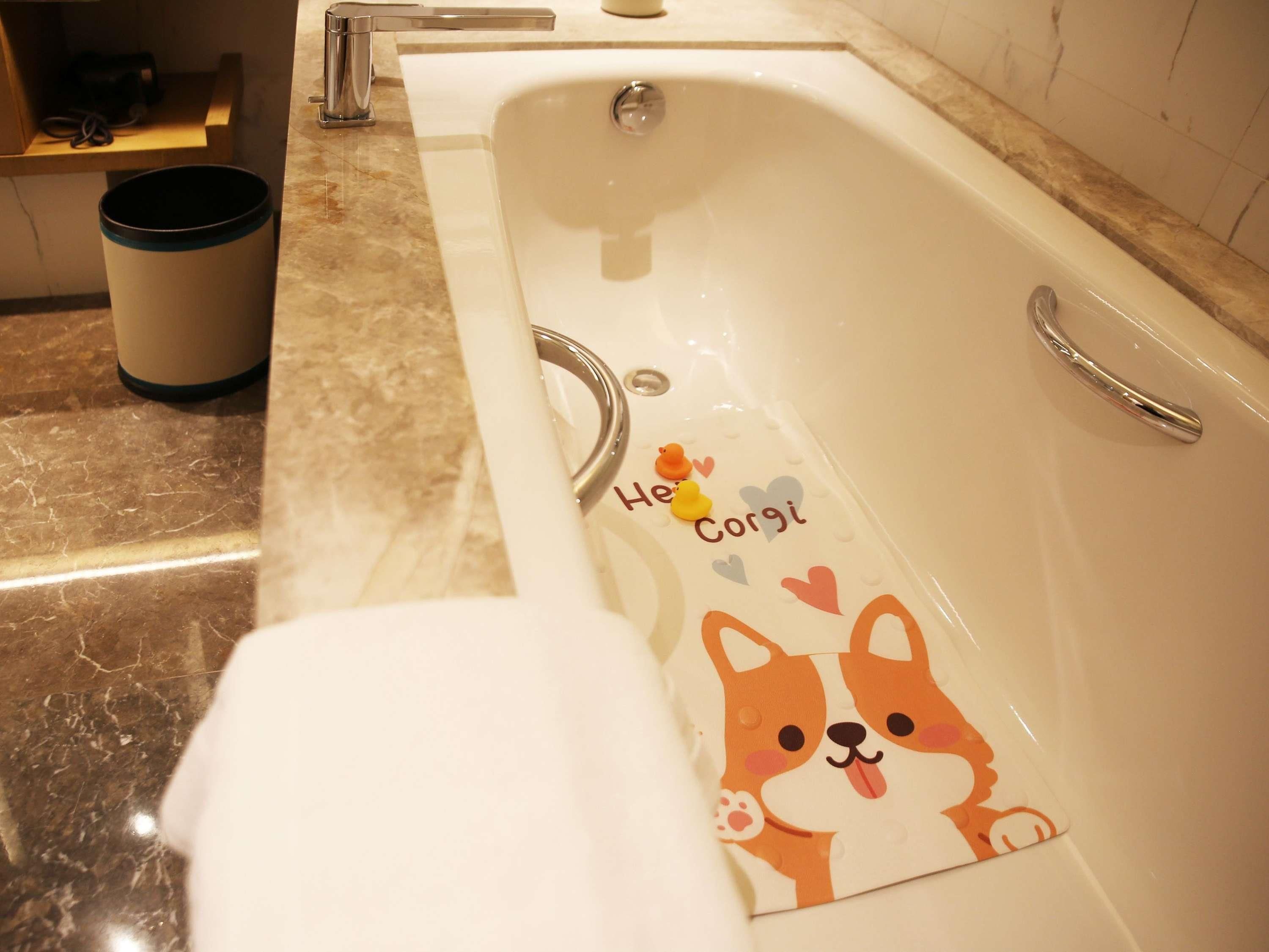 A bathroom with a bathtub, a towel, and a trash bin.