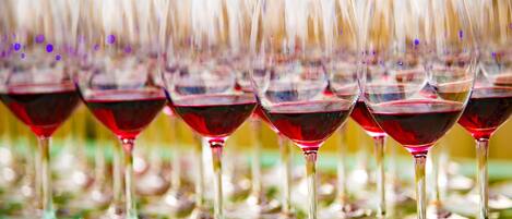 Varias copas de vino tinto sobre una superficie reflectante.