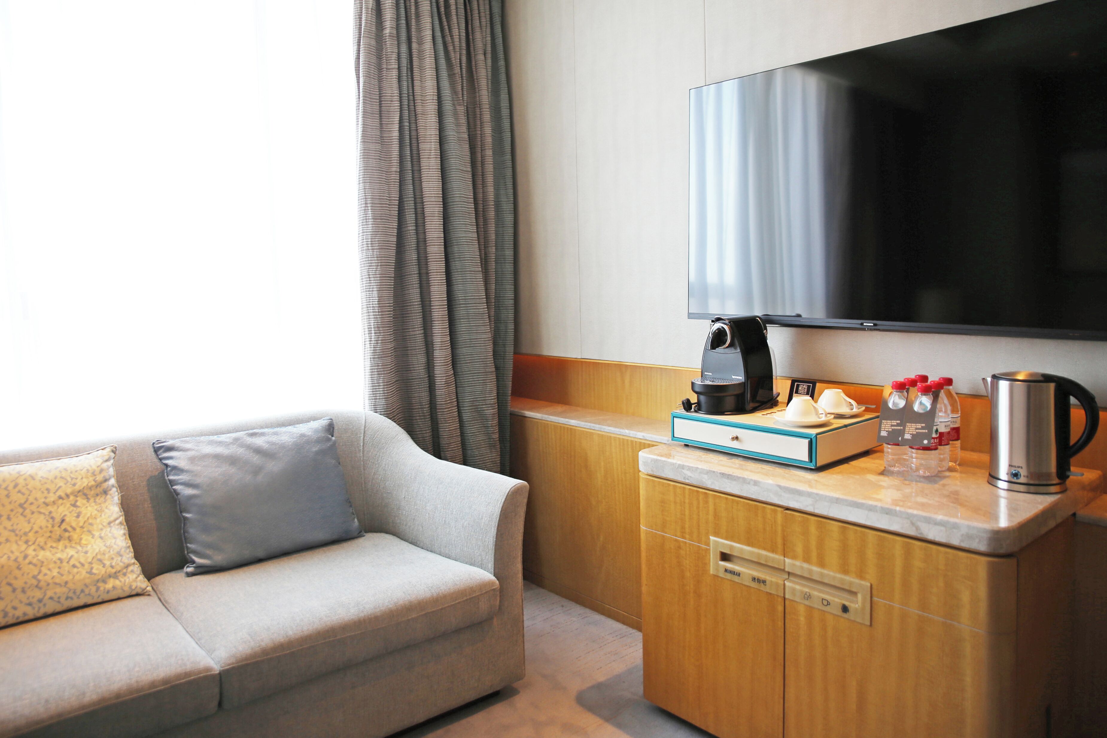 Une chambre d’hôtel équipée d’un canapé, d’une machine à café, d’une bouilloire et d’un téléviseur à écran plat.