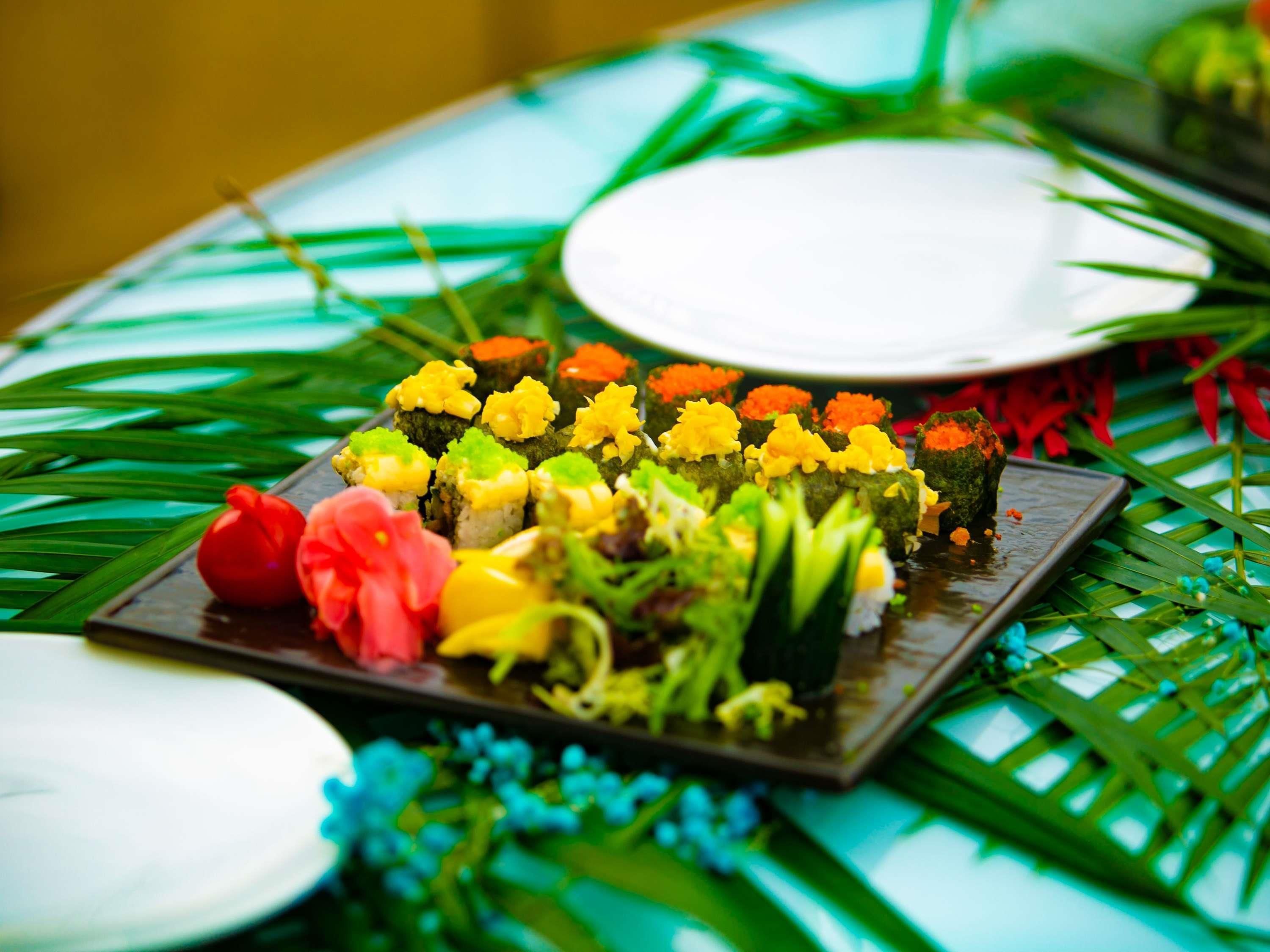 Een tafel met sushi en decoratieve bloemen.