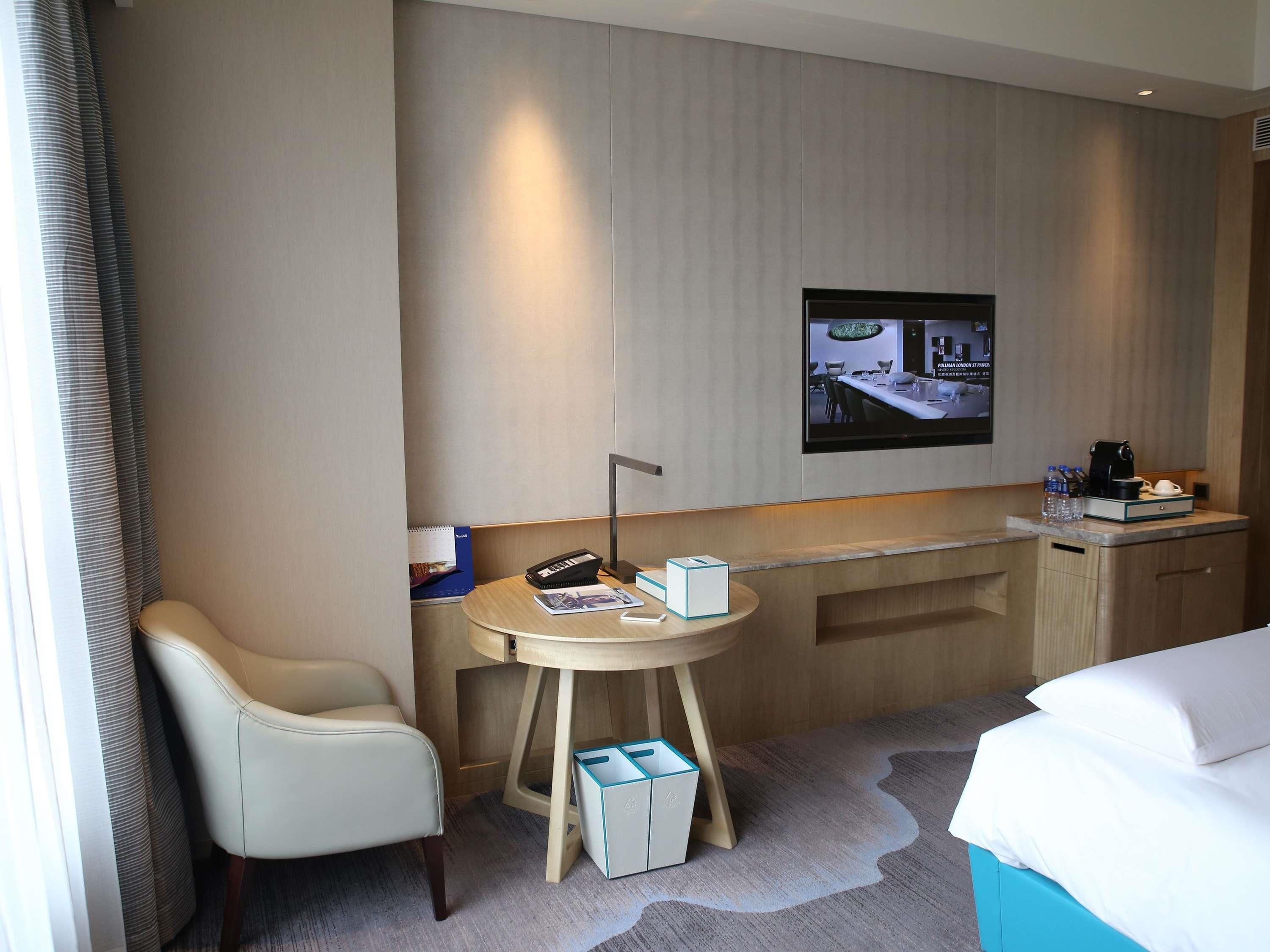 Een hotelkamer met een bed, een bureau, een stoel, een kleine tafel, een televisie en een kast.