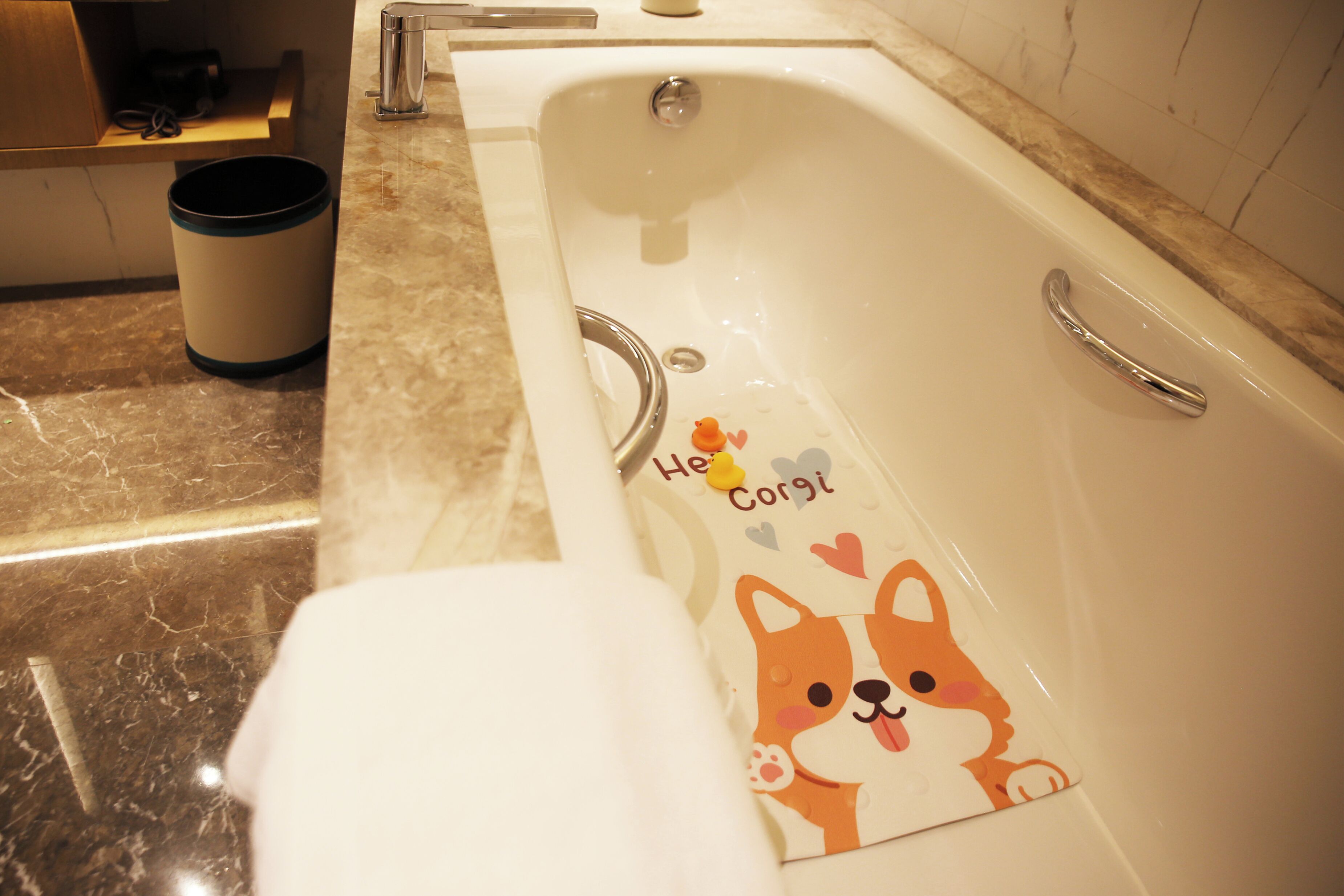Ein Badezimmer mit einer Badewanne, einem Handtuch und einem Mülleimer.
