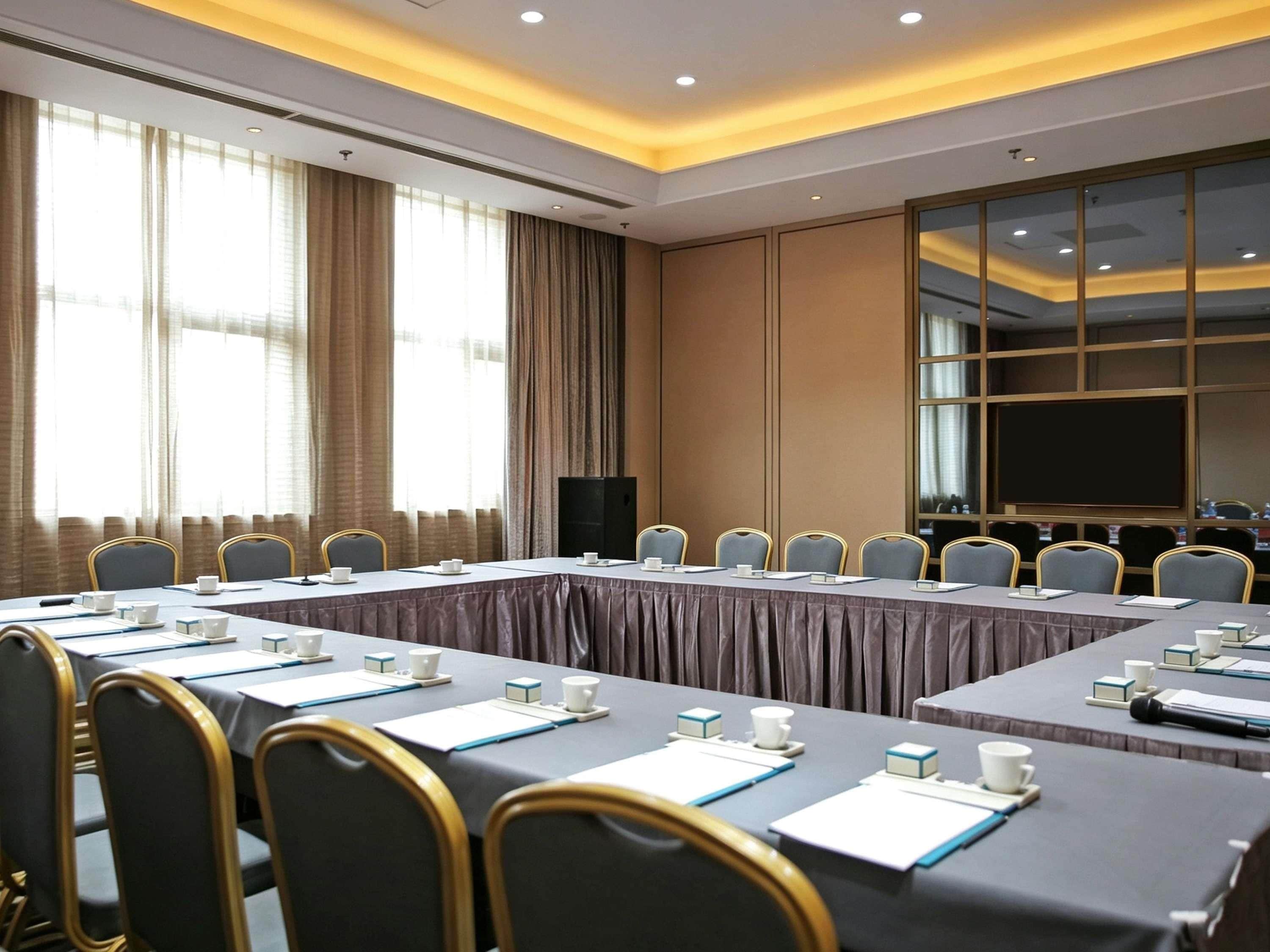Un salón de conferencias con una mesa larga, sillas y una pantalla grande.