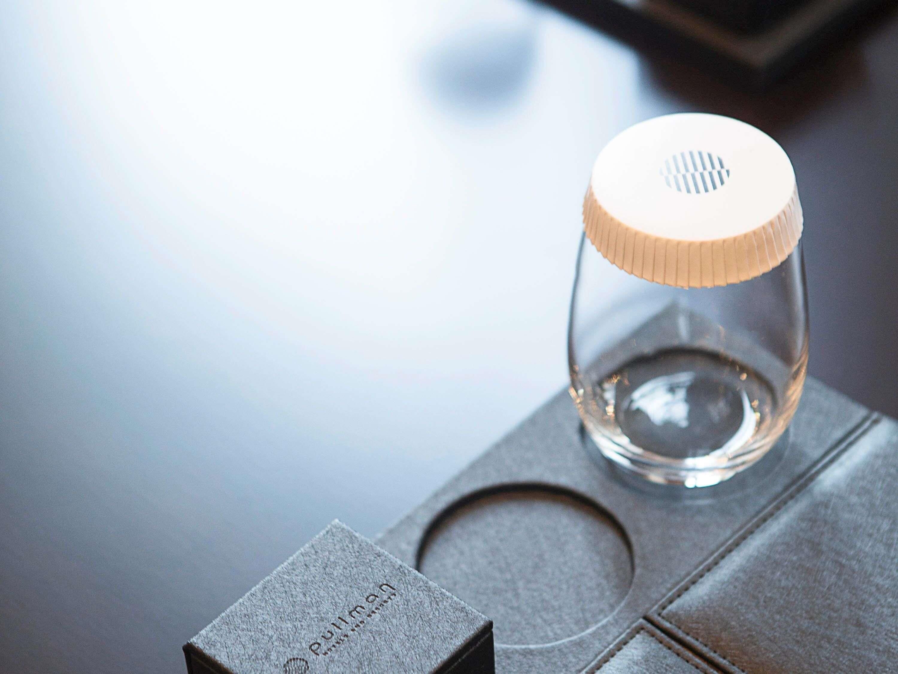 A clear glass bottle with a ribbed cap on a metallic surface.