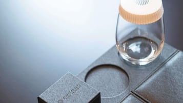 En genomskinlig glasflaska med ett räfflat lock, placerad på en metallisk yta.