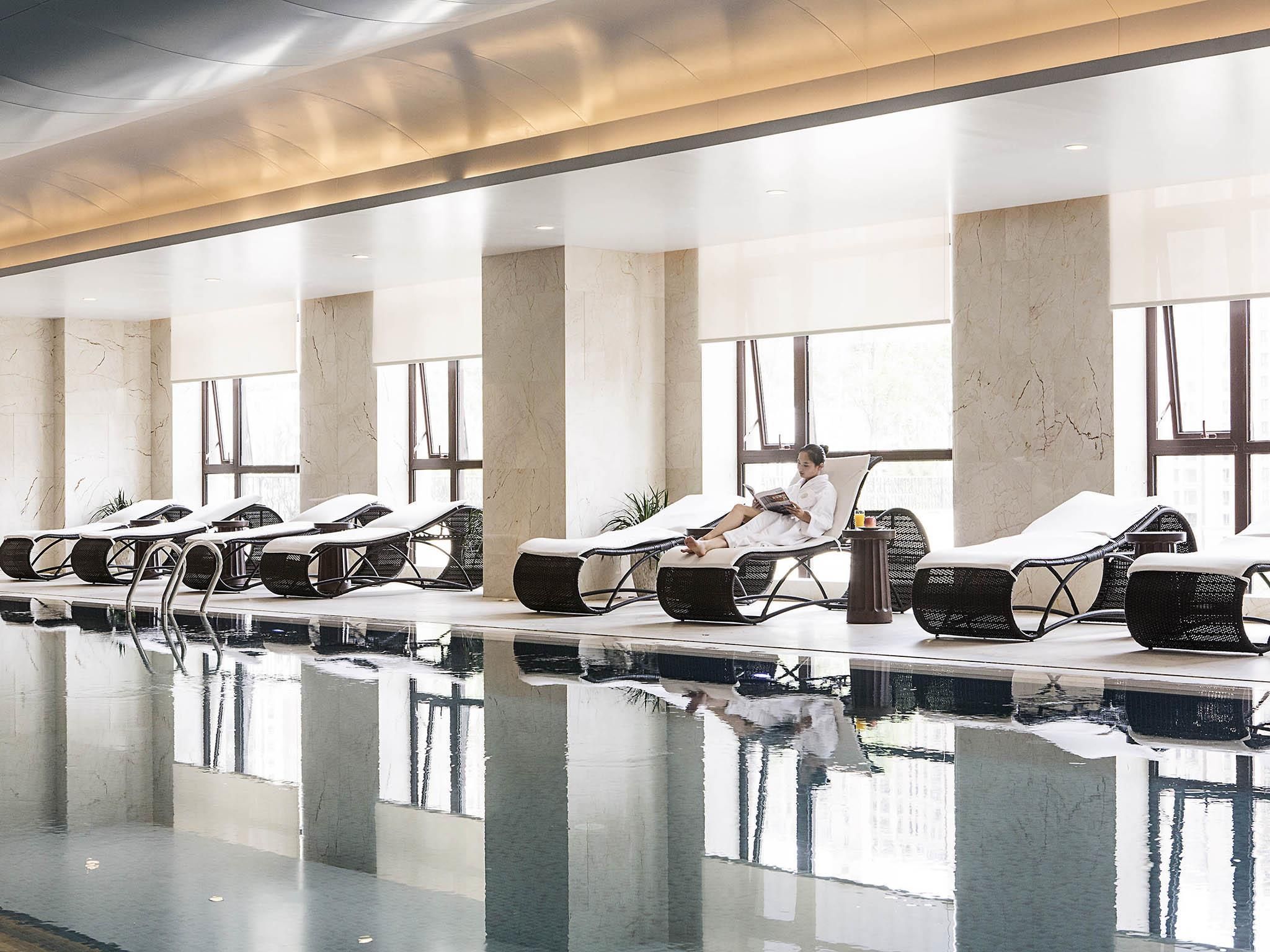 Uma área de spa com cadeiras reclináveis, piscina e grandes janelas.