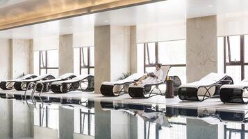 Uma área de spa com cadeiras reclináveis, piscina e grandes janelas.