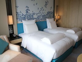 Habitación de hotel con una cama grande, una mesita de noche, una silla y una pared con un diseño abstracto azul.