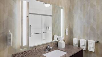 A bathroom with a granite countertop, a white sink, a large mirror, and a towel rack.
