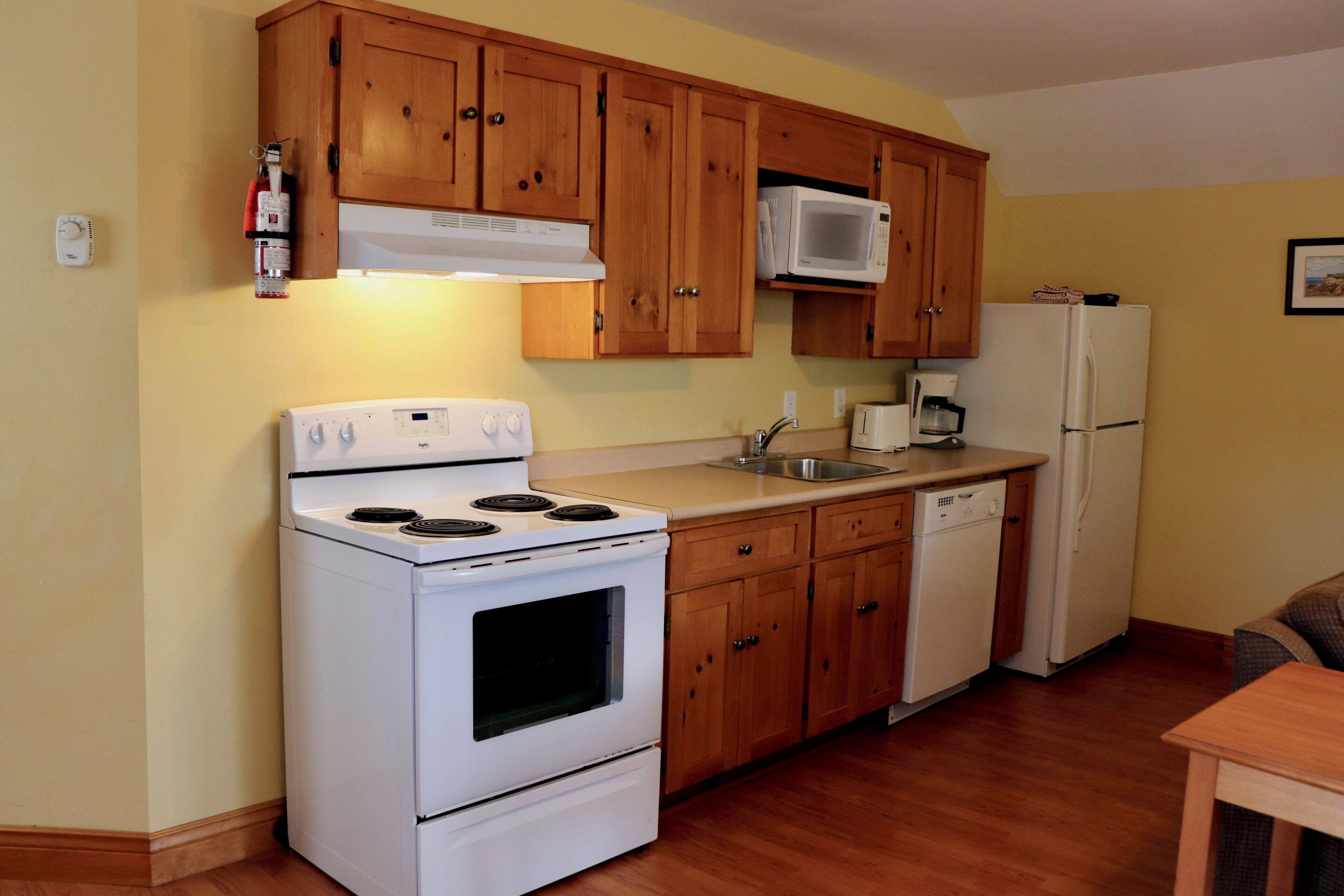 Una cocina con armarios de madera, una estufa blanca, un microondas, un lavavajillas y un refrigerador.