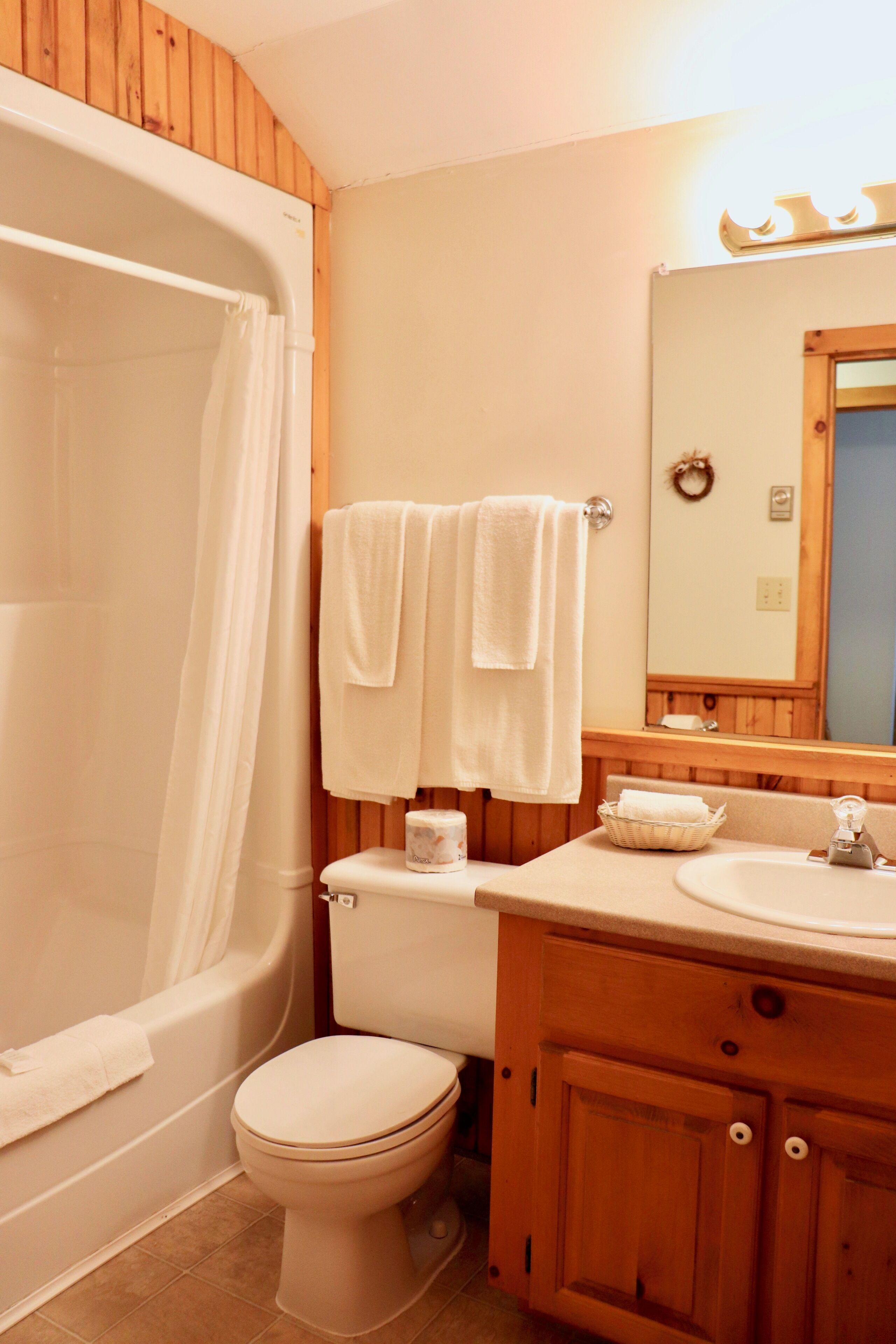 A bathroom with a bathtub, toilet, and wooden vanity.