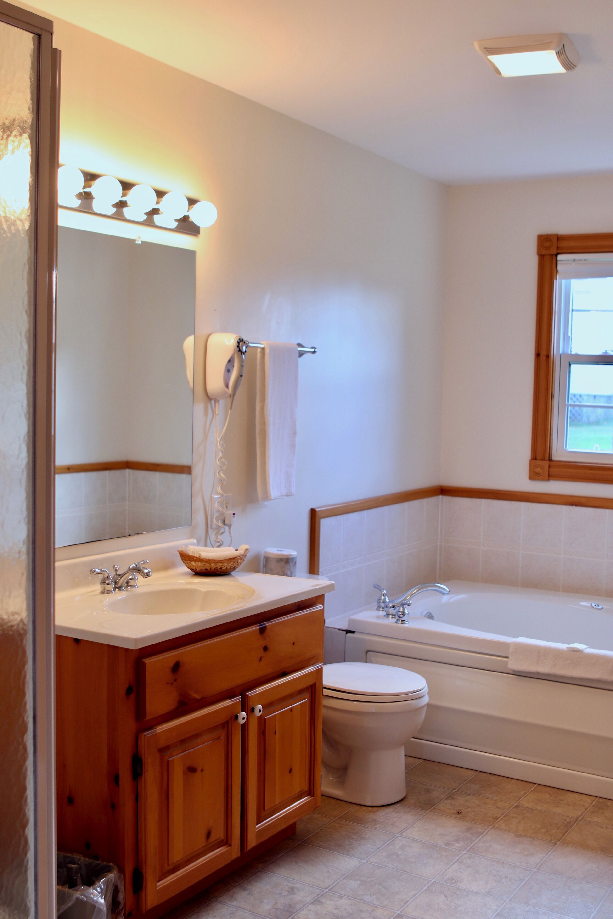 A bathroom with a wooden vanity, a sink, a toilet, and a bathtub.