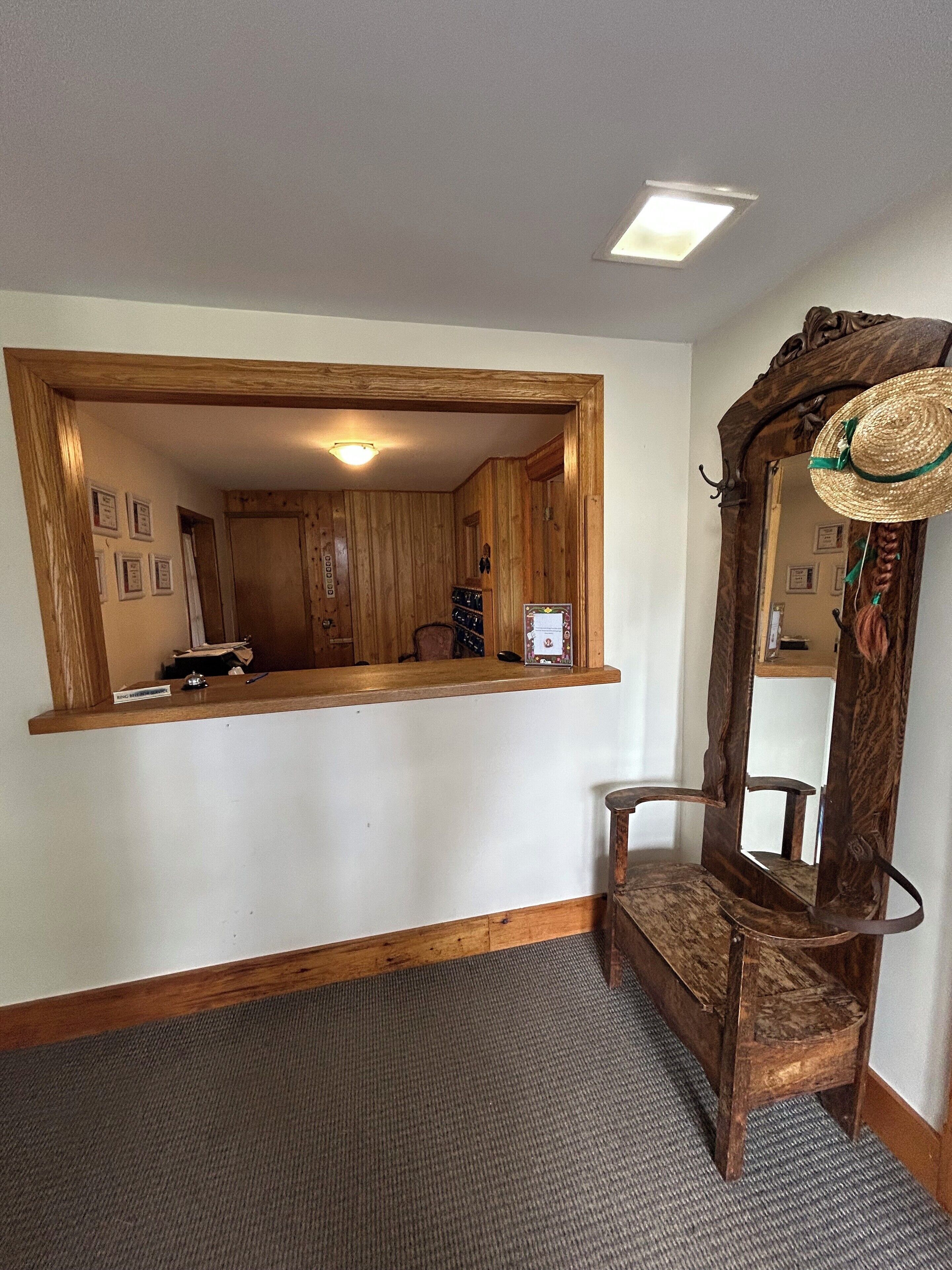 A room with a wooden vanity, a mirror with a decorative frame, and a small stool.