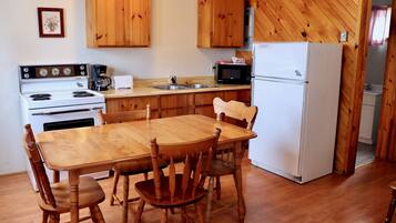 Una cucina con mobili in legno, un piano cottura bianco, un forno a microonde e un frigorifero.