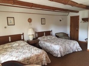 A room with two beds, a nightstand with a lamp, and a chair. - Dalem's Chalet (Brattleboro)