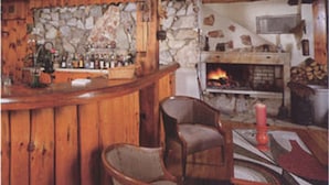 Un interior rústico con pared de piedra, barra de madera y chimenea.