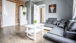 En moderne stue med en grå sofa, et hvidt sofabord og en væg med murstensudsmykning.