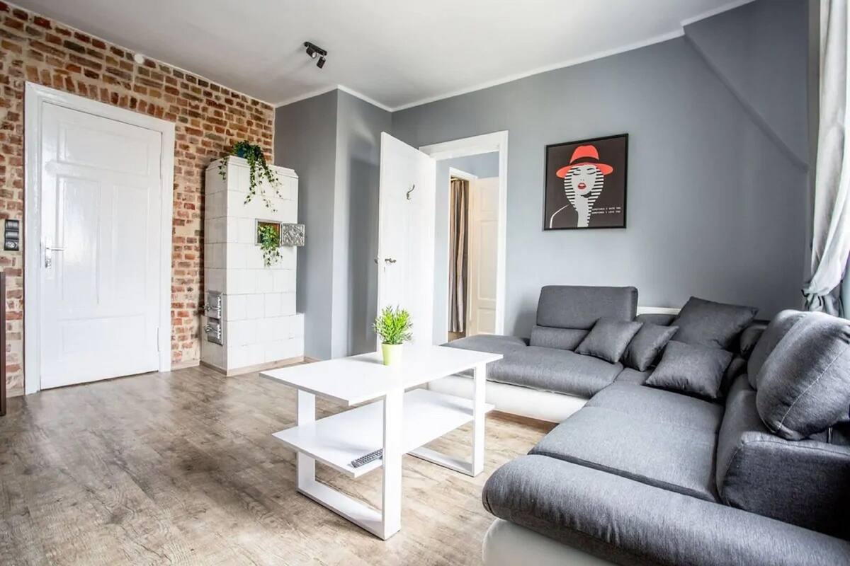 A modern living room with a gray sofa, a white coffee table, and a brick accent wall.