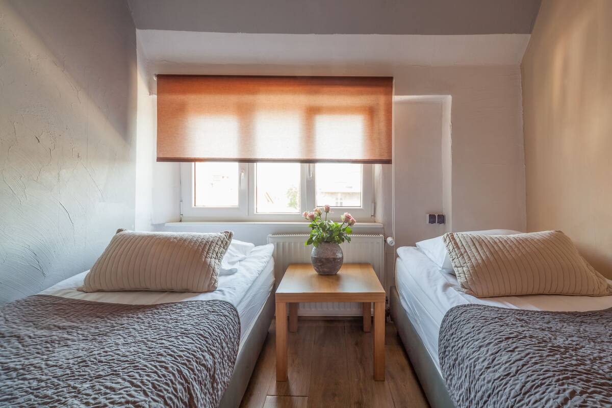 A small, cozy room with two beds, a small table, and a window with a view.