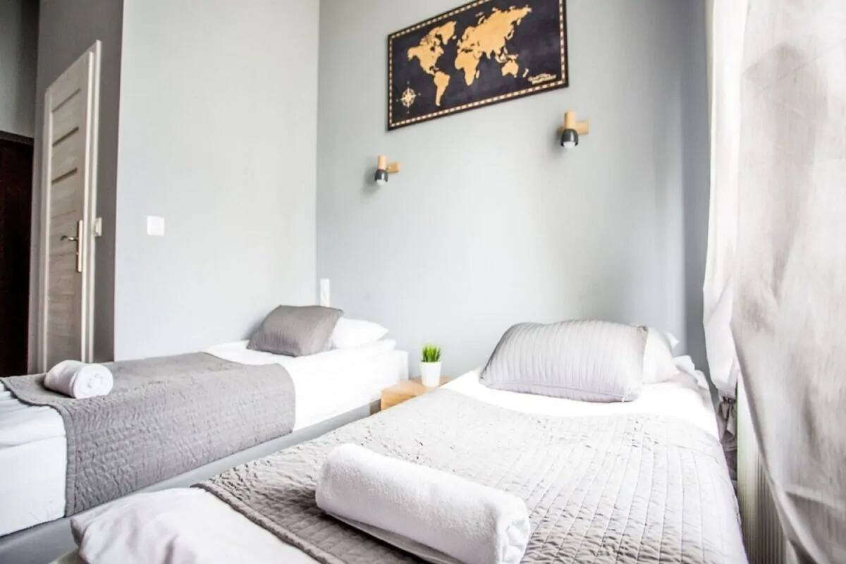 A hotel room with two beds, a world map on the wall, and a small plant on the nightstand.