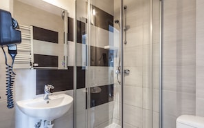 A modern bathroom with a glass-enclosed shower, a white sink, and a hairdryer on a wall-mounted rack. - Central Sopot (Sopot)