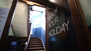 En trappe fører op til et rum, hvor der står skilt med teksten 'ENJOY YOUR HOLIDAY'.