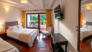 A hotel room with two beds, a TV, a desk, and a view of the outdoors. - Hotel Meson de los Virreyes (Villa de Leyva)