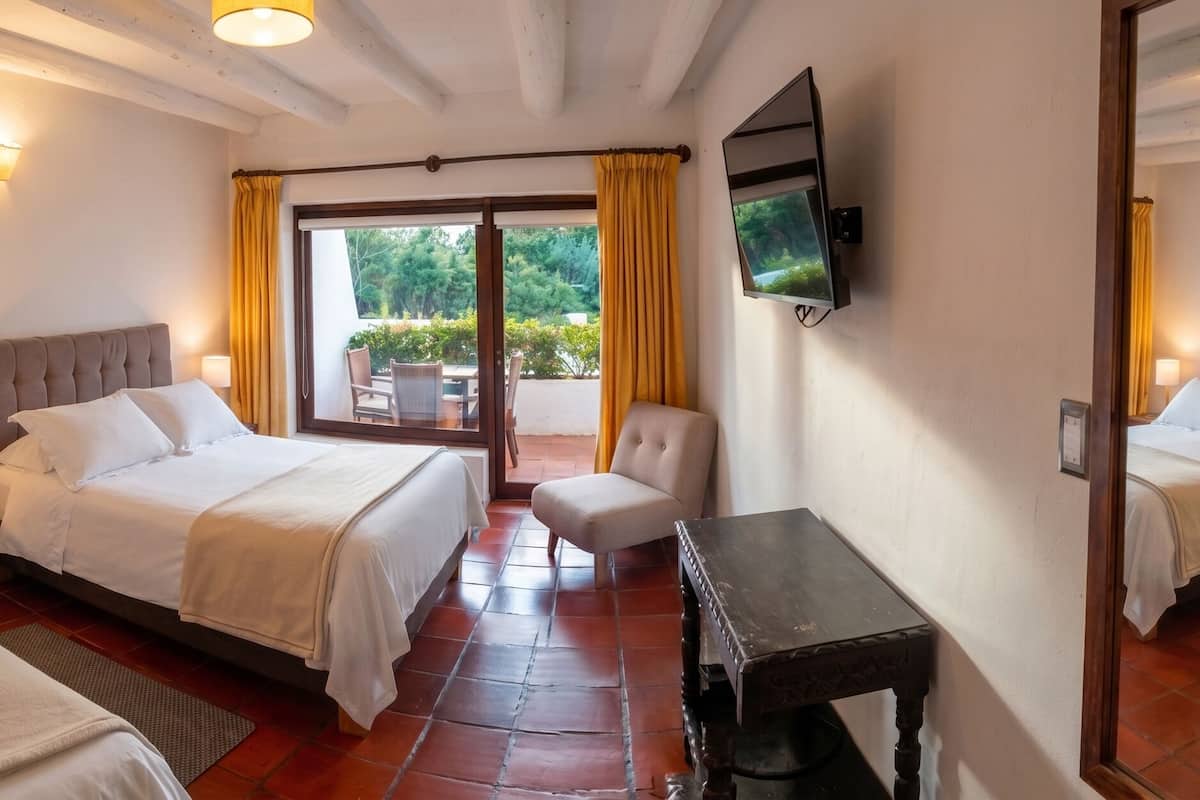 Een hotelkamer met twee bedden, een televisie, een bureau en uitzicht op de omgeving.